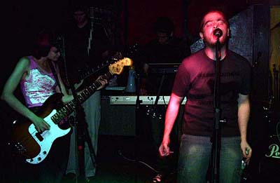 Musicians on stage under green and red lights.